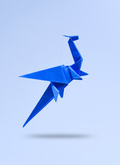 Blue Origami dragon levitating on a pastel background