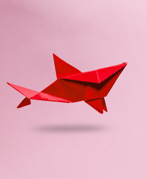 Red Origami shark levitating on pink