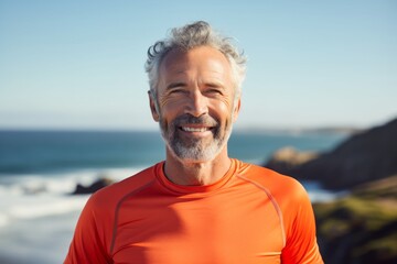 Fototapeta na wymiar Portrait of a happy man in his 50s sporting a breathable mesh jersey over serene seaside background