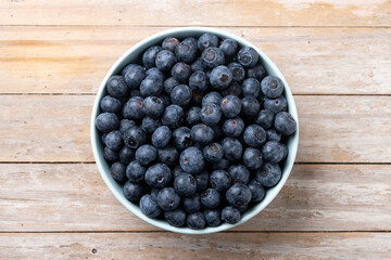 Blueberries in green bowl on wooden table. Top view - 788106512