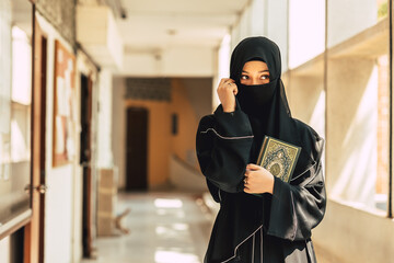 Muslim niqab woman read and learning the Quran and faith The Holy Al Quran book. Arab saudi black chador lady.arabic calligraphy translate meaning of Al Quran