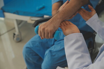 Obraz premium Physiotherapist man giving exercise with dumbbell treatment About Arm and Shoulder of athlete male patient Physical therapy concept