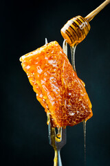 Honey stick and Honeycombs on a metal fork. Macro photo. Organic honey.