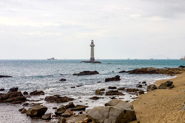 View of the lighthouse in the sea near the rocky shore. End of the World Park, Sanya, China