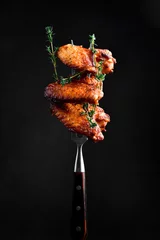  Traditional Buffalo BBQ chicken wings, on a fork. On a black background. © Yaruniv-Studio