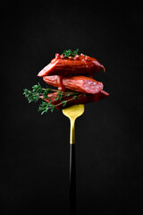 Bavarian sausages with ketchup on a fork. Close up. On a black background. - 788117165