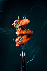 Fork with baked chicken wings, salt and smoke in the photo. Traditional Buffalo Chicken Wings.