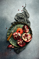 Vintage metal tray with a piece of fresh pomegranate. On a concrete background. Rustic style.