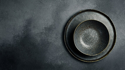 A set of dark ceramic bowls and plates. Close up on gray concrete background. Free space for text. - 788117986