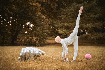 Portrait of young hairless girl ballerina with alopecia in white cloth playing with tardigrade toy in fall park, surreal scene with bald teenage girl reflect on intertwining threads of life and art