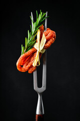 Dried pork sausages on a metal fork. Kabanos Close up on a black background. - obrazy, fototapety, plakaty