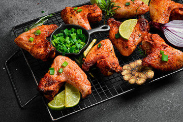 Baked chicken wings on a metal grill. On a dark background.