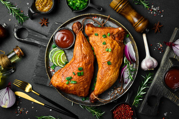 Smoked chicken legs on a black plate with lemon, rosemary and spices. On a dark background. - 788119140