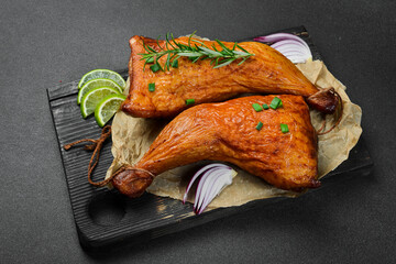 Baked chicken legs on a wooden board. Grilled chicken, grilled chicken legs. On a dark background.