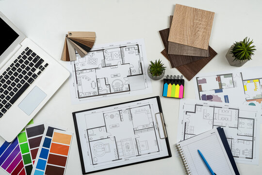 Interior designer's working table with laptop tools wooden color sampler and blueprints of the project
