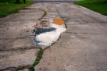 The concrete road is damaged and waterlogged.