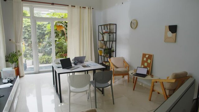 Pan shot of small office of IT startup company with working tables, nobody around