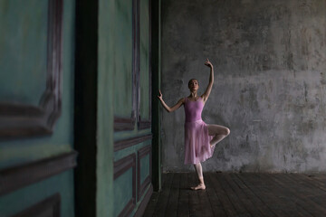 Slender ballerina in a pink suit warms up before dancing