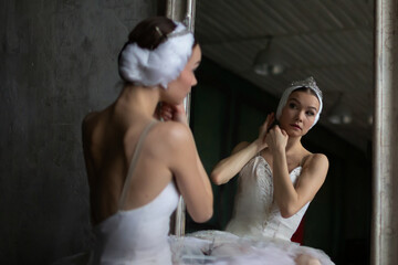 Ballerina sits in front of a mirror and adjusts her costume before her dance