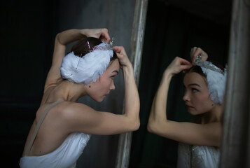 Ballerina sits in front of a mirror and adjusts her tiara before dance