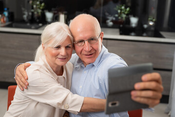 Smiling senior couple taking selfie at home