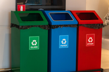 Close-up of green, blue, and red trash cans for separate dumping of glass, paper, and other trash in the store. Concept of proper waste disposal.