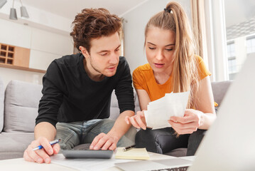 Worried young Caucasian couple going over bills