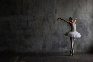 Ballerina in a white tutu performs a dance element from ballet.