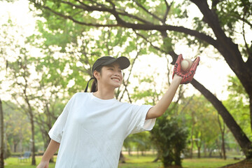 Shot of teenage Asian girl wearing leather glove playing baseball in the park