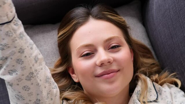 Close up portrait of a cheerful and peaceful Caucasian woman awake in the morning and stretching to camera at home. Resting, relaxing concept.