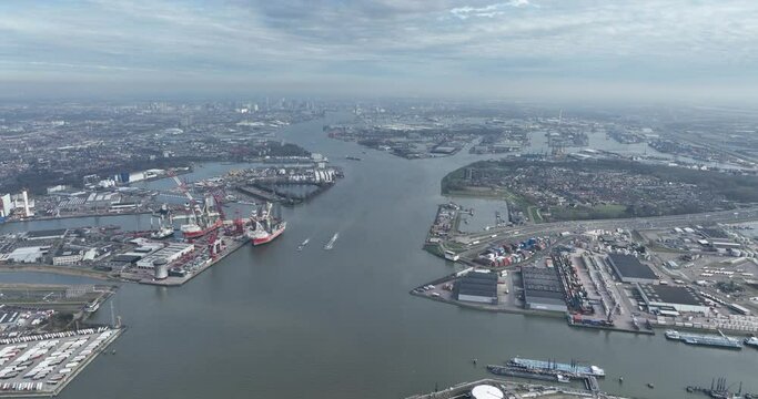 Aerial high altitude drone overview of the port of Rotterdam, Schiedam, Vlaardingen and Pernis. Nieuwe Maas river and skyline of Rotterdam in the background.