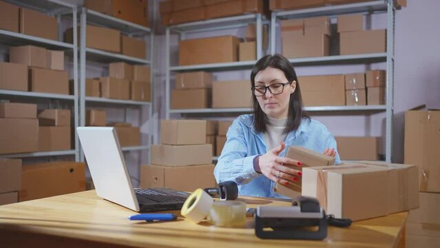 A young female warehouse worker uses a barcode scanner in her work
