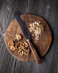 Chopped walnuts and knife on wooden plate. Crushed walnut kernels close up. Food photography