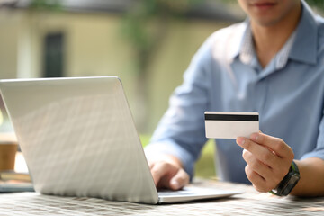Cropped shot of man holding credit card and using laptop for making online payments