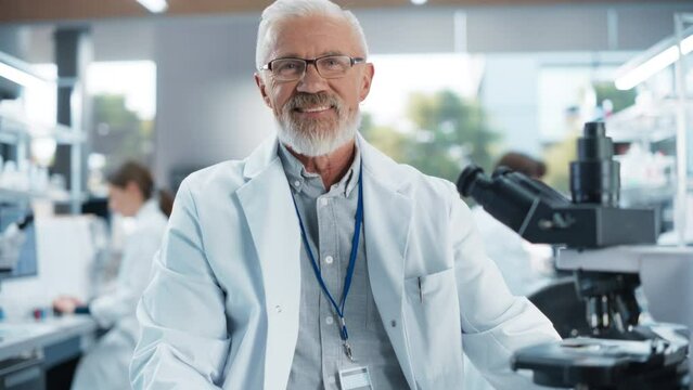 Portrait of a Senior Scientist Posing for Camera, Smiling. Middle Aged Male Biologist in a White Coat Working in a Modern Laboratory, Researching Medical Drug Products and Genome Editing