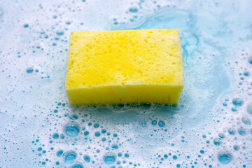 Cleaning sponge in foam of dishwashing liquid. Washing dishes concept