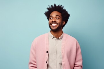 Portrait of a jovial afro-american man in his 20s wearing a chic cardigan in front of pastel or soft colors background
