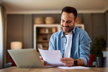 A smiling young adult man reading his resume before applying for a new job.