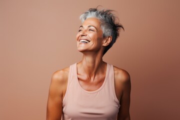 Portrait of a joyful woman in her 50s dressed in a breathable mesh vest in minimalist or empty room background