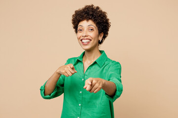 Young woman of African American ethnicity wear green shirt casual clothes point index finger camera on you motivate encourage isolated on plain pastel light beige background studio Lifestyle concept