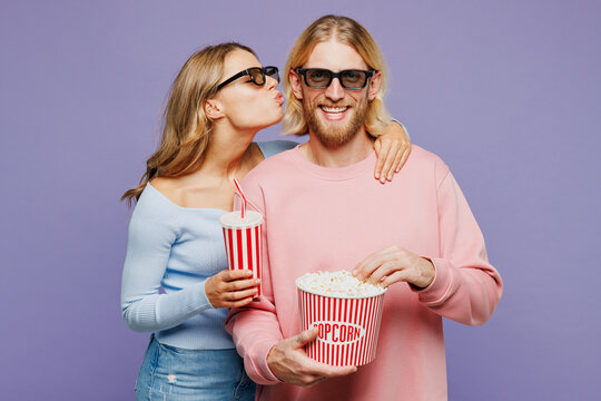 Young couple two friends family man woman wear pink blue casual clothes 3d glasses watch movie film hold bucket of popcorn cup of soda pop in cinema together kiss isolated on plain purple background.