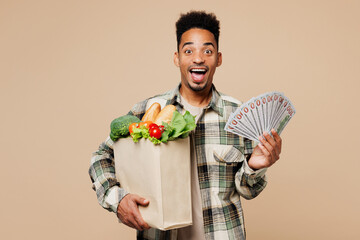 Young man wears grey shirt hold paper bag for takeaway mock up with food products, fan of cash...