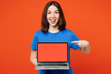 Young shocked happy IT woman she wear blue t-shirt casual clothes hold use work on laptop pc computer with blank screen workspace area isolated on plain red orange background studio Lifestyle concept