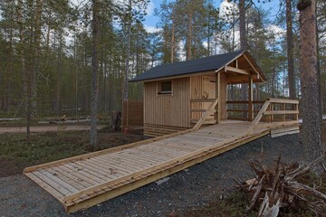 Outdoor wood toilet in nature at Nurmiselkä lake in cloudy spring weather, Hossa National Park,...