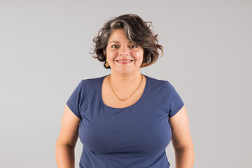 A woman with a blue shirt and a gold necklace is smiling