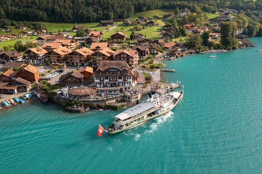 Iseltwald, Switzerland - September 11 2021: Aerial view of the traditional L&ouml;tschberg paddle steamer cruise ship that arrives at the Iseltwald pier, a famous village by lake Brienz in Bern