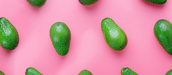Green avocados arranged in a minimal flat lay style on a pink background, a pop art design representing a creative summer food concept. Top view banner image.