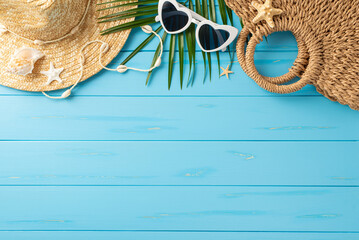 A top view of summer vacation essentials including a straw hat, sunglasses, beach bag, and tropical leaves on a bright blue wooden surface, conveying the concept of holiday and relaxation - Powered by Adobe