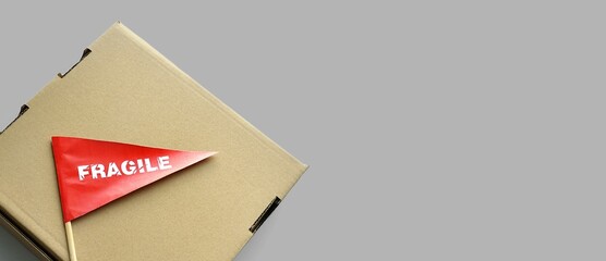 One cardboard packaging box on monochrome background. Tiny red paper flag with the warning...
