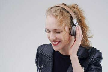 Relax, music or happy woman in headphones in studio for singing or streaming on grey background....